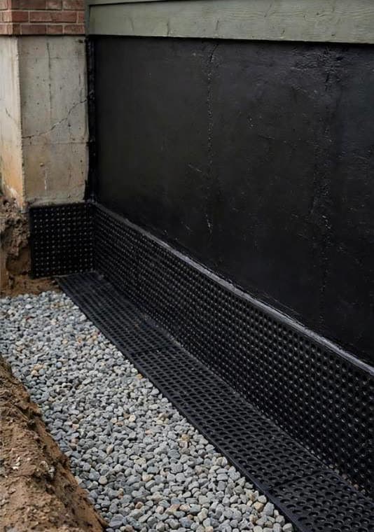 Finished exterior system: black membrane, dimple board at the footing and clear gravel